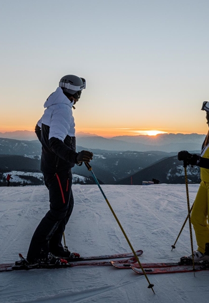 Due persone con gli sci guardano il tramonto